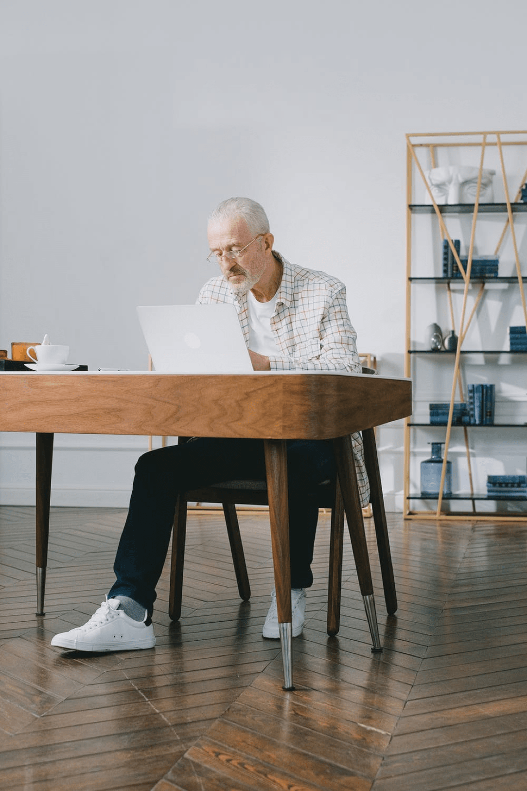 Älterer Mann mit Brille sitzt an einem Schreibtisch vor dem PC