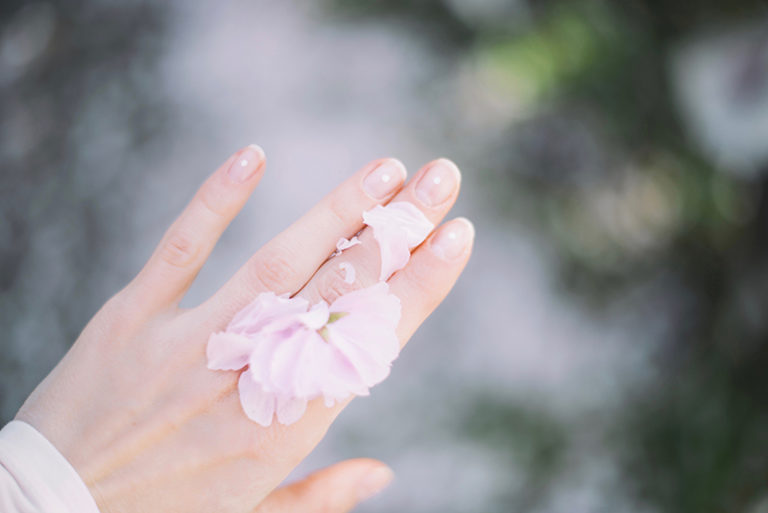 Frauenhand mit hellen Blüten im Blog-Artikel zu Schminken mit Kontaktlinsen von Optiker Gronde, Augsburg 