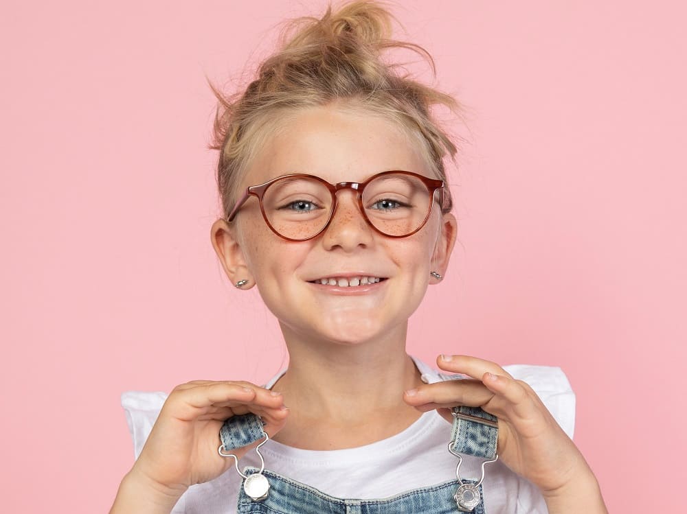 Junges Mädchen mit frechem Blick und roter Lieblings-Brille von Optiker Gronde