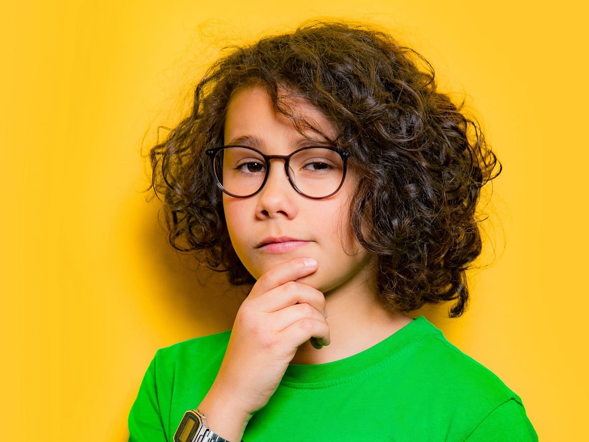 Junge mit grünem T-Shirt und dunklen Locken blickt nachdenklich auf der 404 Fehler Seite (nicht gefunden) von GRONDE Sehen & Hören