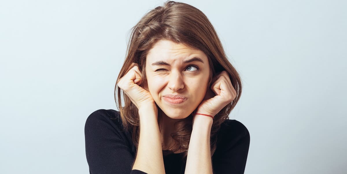 Junge Frau hält sich die Ohren zu: Braucht Gehörschutz von Hörakustik GRONDE