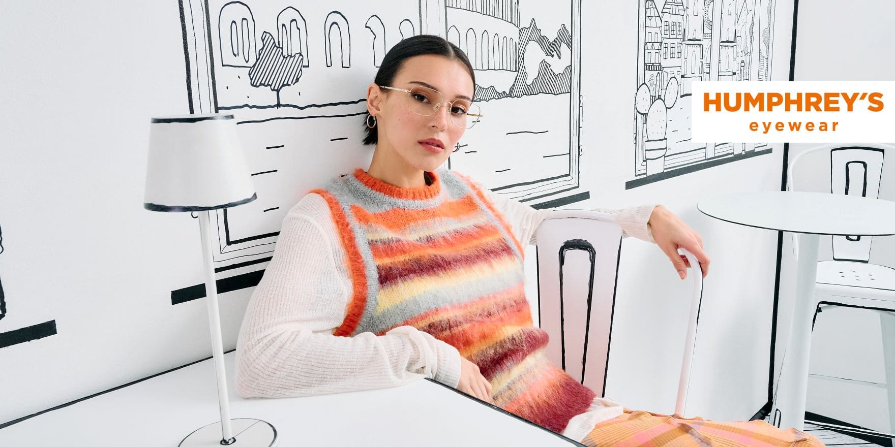 Schwarzhaarige Frau mit zurückgegelten Haaren blickt in die Kamera. Sie trägt eine feine goldene Brille der Marke Humphrey´s