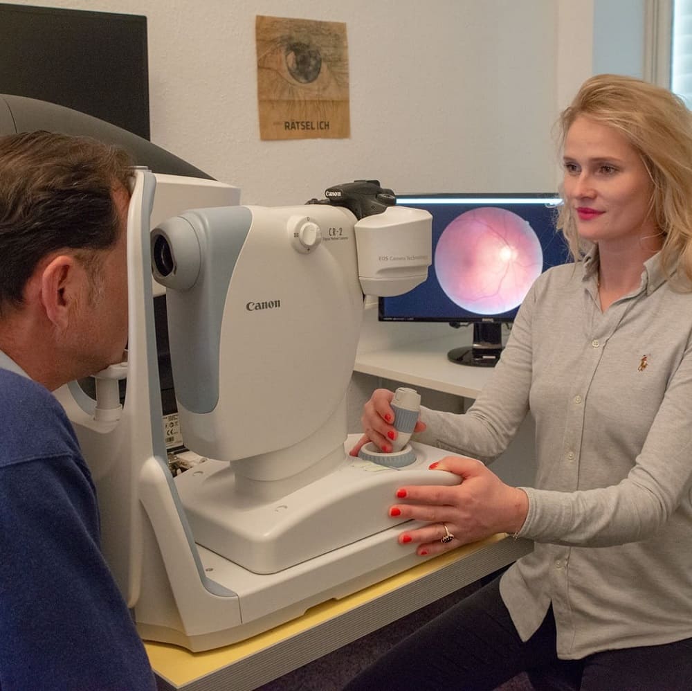 Junge Optikern bei Gronde schaut Kunden mit der Funduskamera tief ins Auge bis auf die Netzhaut