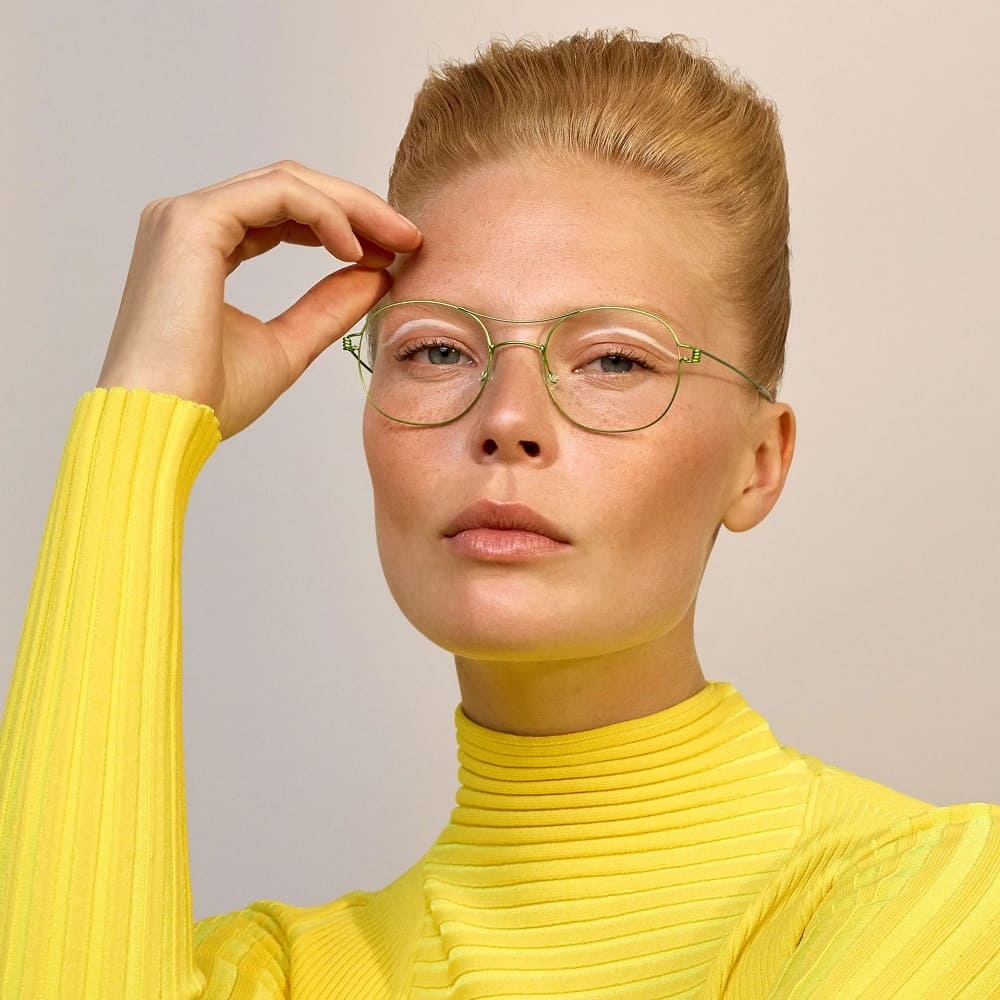 Kurzhaarige Blondine mit gelbem Pulli und grüner Lindberg Brille von Optiker Gronde