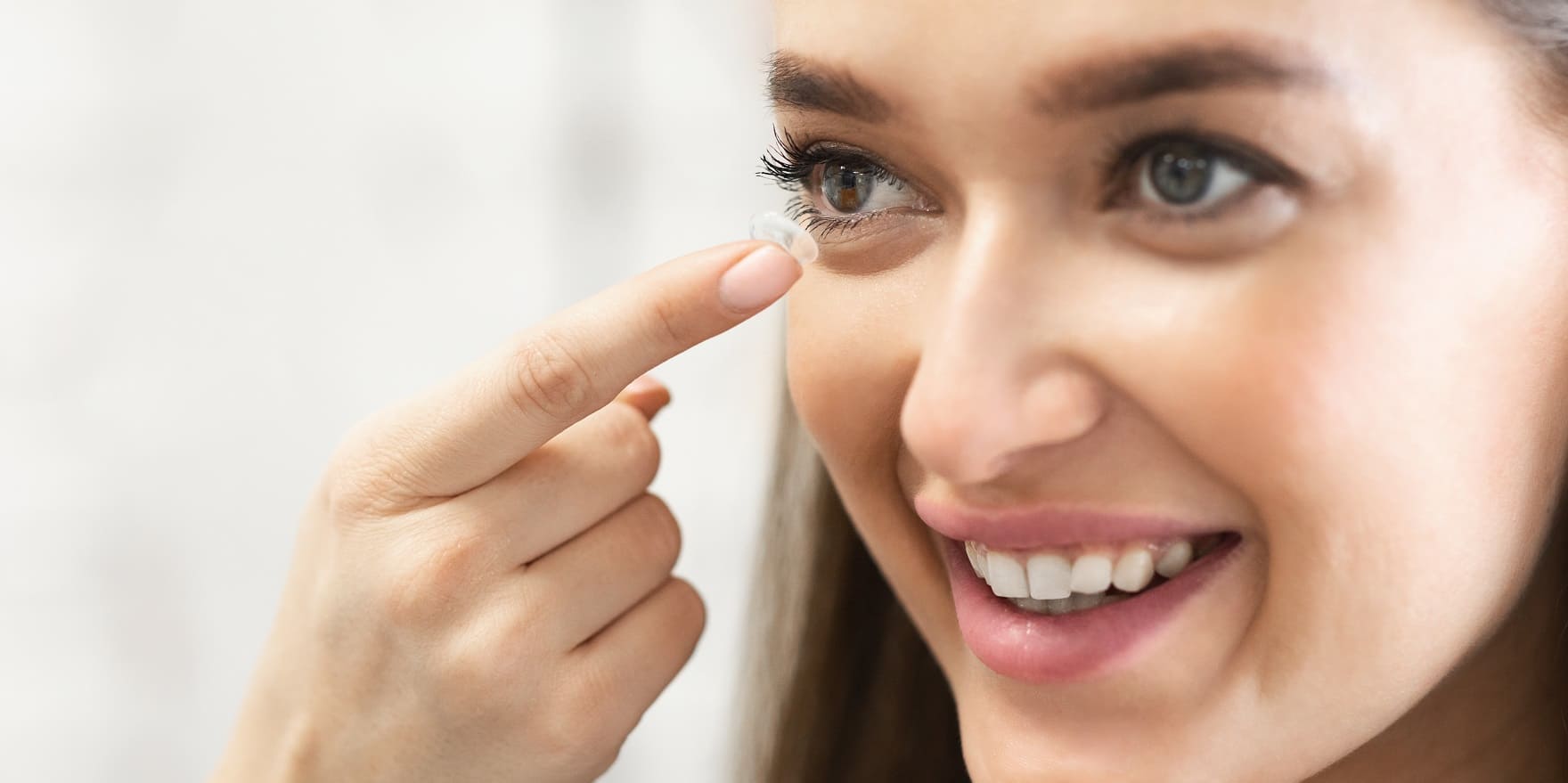 Junge Frau übt Einsetzen ihrer harten Kontaktlinsen bei Optiker Gronde