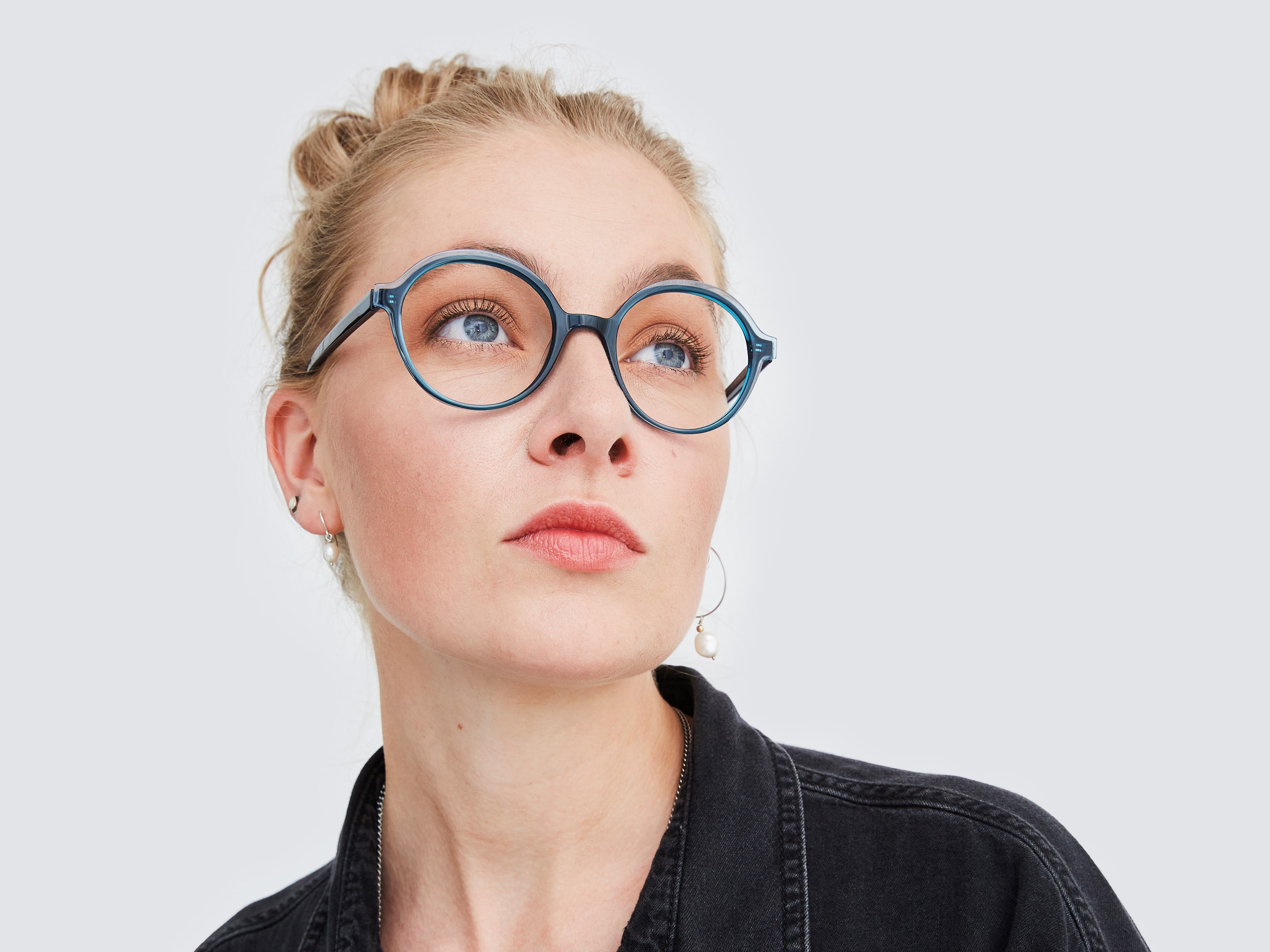 Blondine mit hochgesteckten Haaren und blauer, runder Prodesign Brille zeigt die Brillen Trends 2023 im Blog von Optiker Gronde