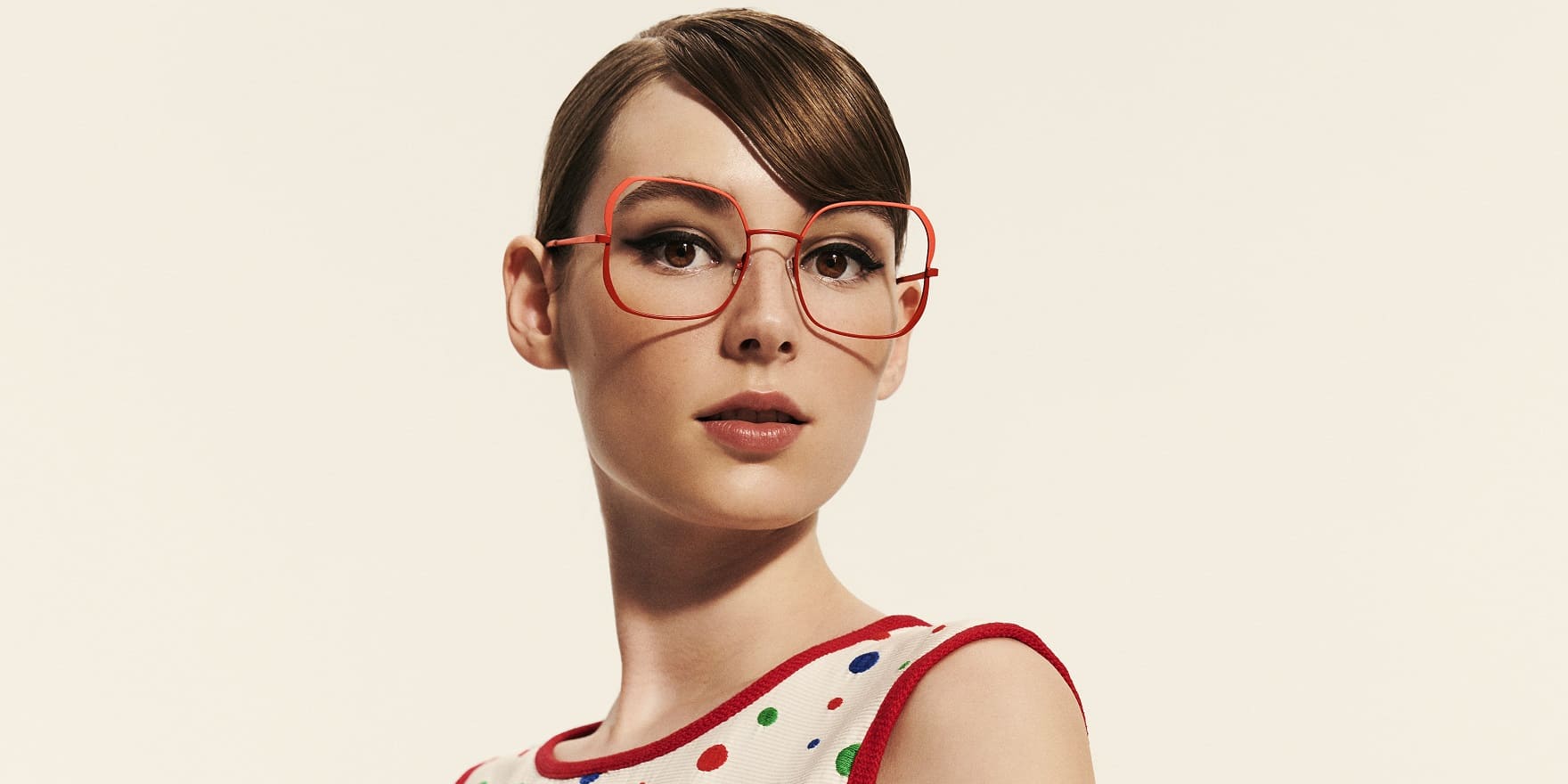 Junge Frau mit witziger oranger Brille von Optiker Gronde und Tupfenkleid
