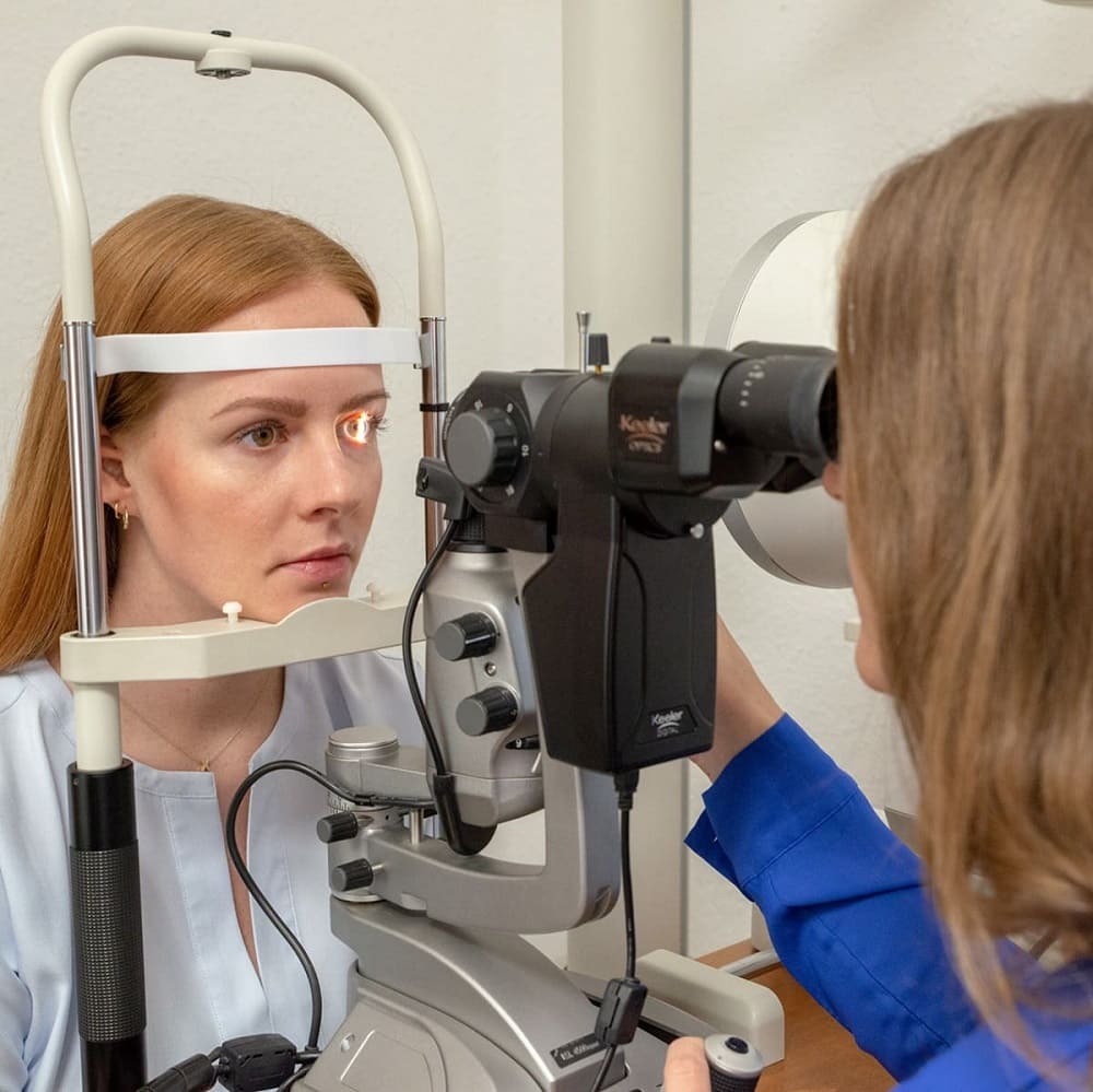 Optikerin von Gronde sieht Kundin mit Spaltlampe ins Auge. Auch das ist Optometrie, und gehört zum optometrischen Screening