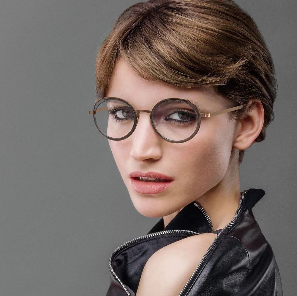 schöne zweifarbige Lindberg Brille in Rauchgrau und Kupfer von Optiker Gronde an attraktiver kurzhaariger Frau mit Leder-Top