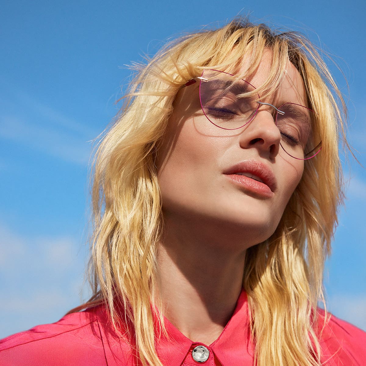 Blonde Frau mit geschlossenen Augen, roter Bluse und zarter, roter Cateye Silhouette Brille TMA LaLigne von Optiker Gronde