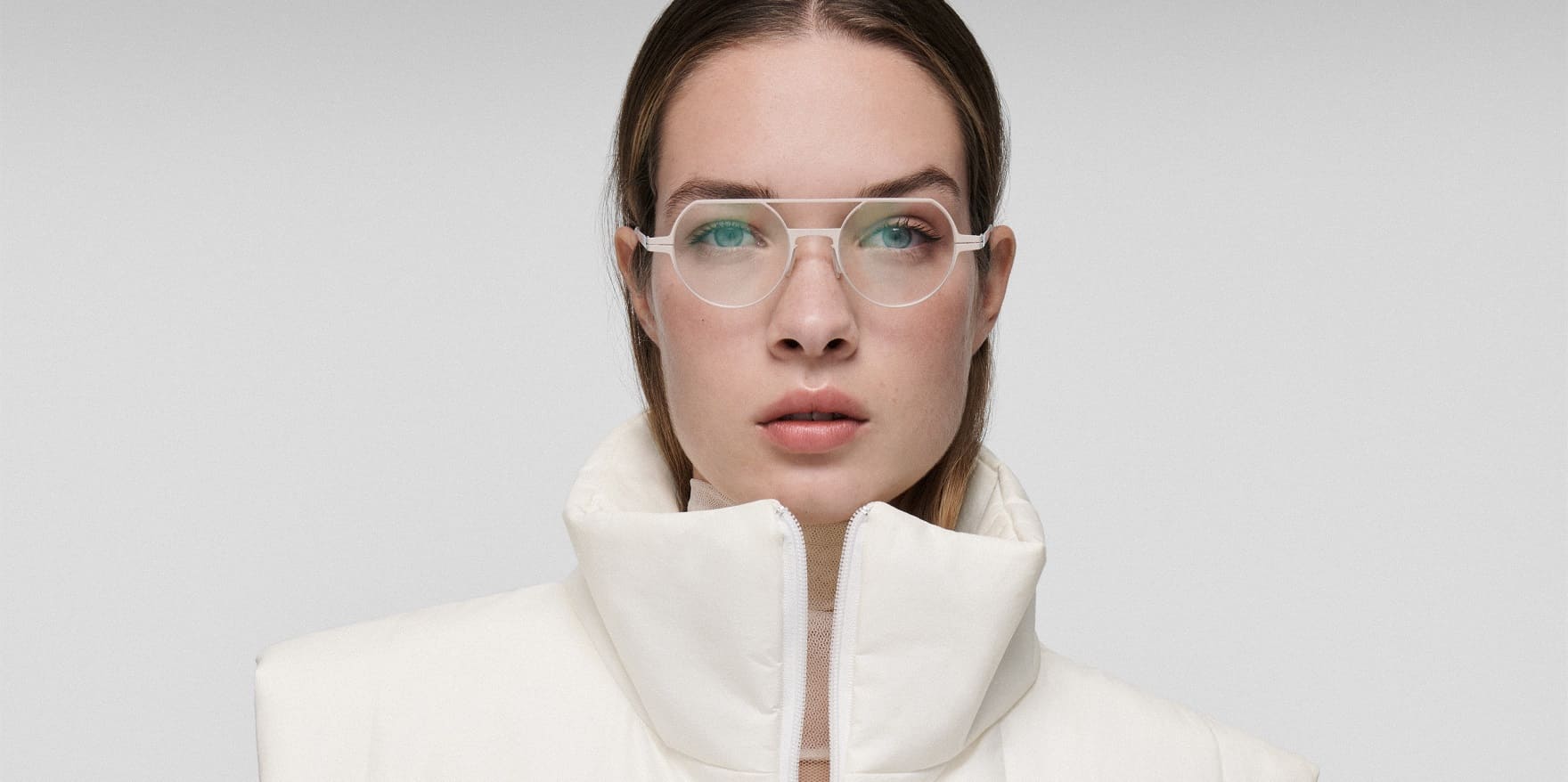 Junge Frau mit weißer Lool-Brille und weißem modernen Outfit. Optiker GRONDE Sehen & Hören