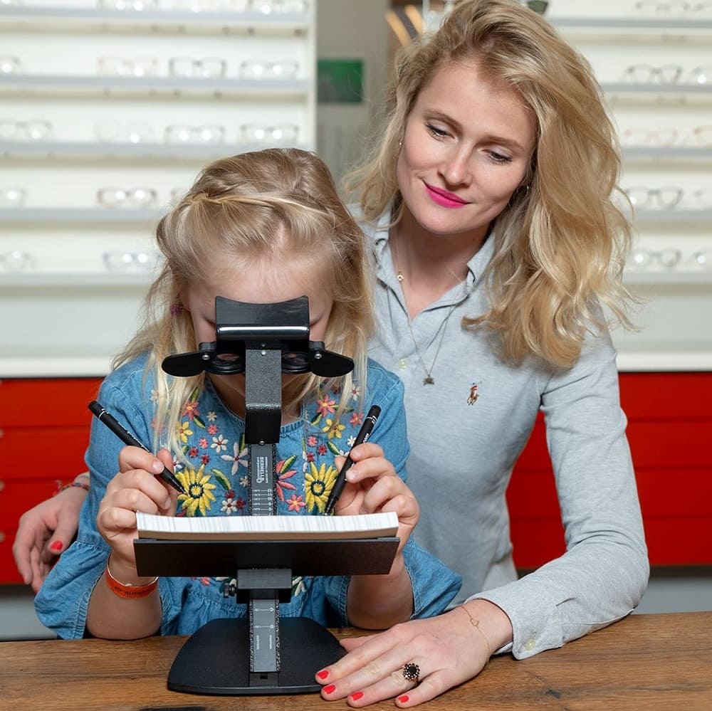 Optometrie: Junge Optikerin bei Gronde test mit blondem Mädchen die Auge-Hand-Koordination