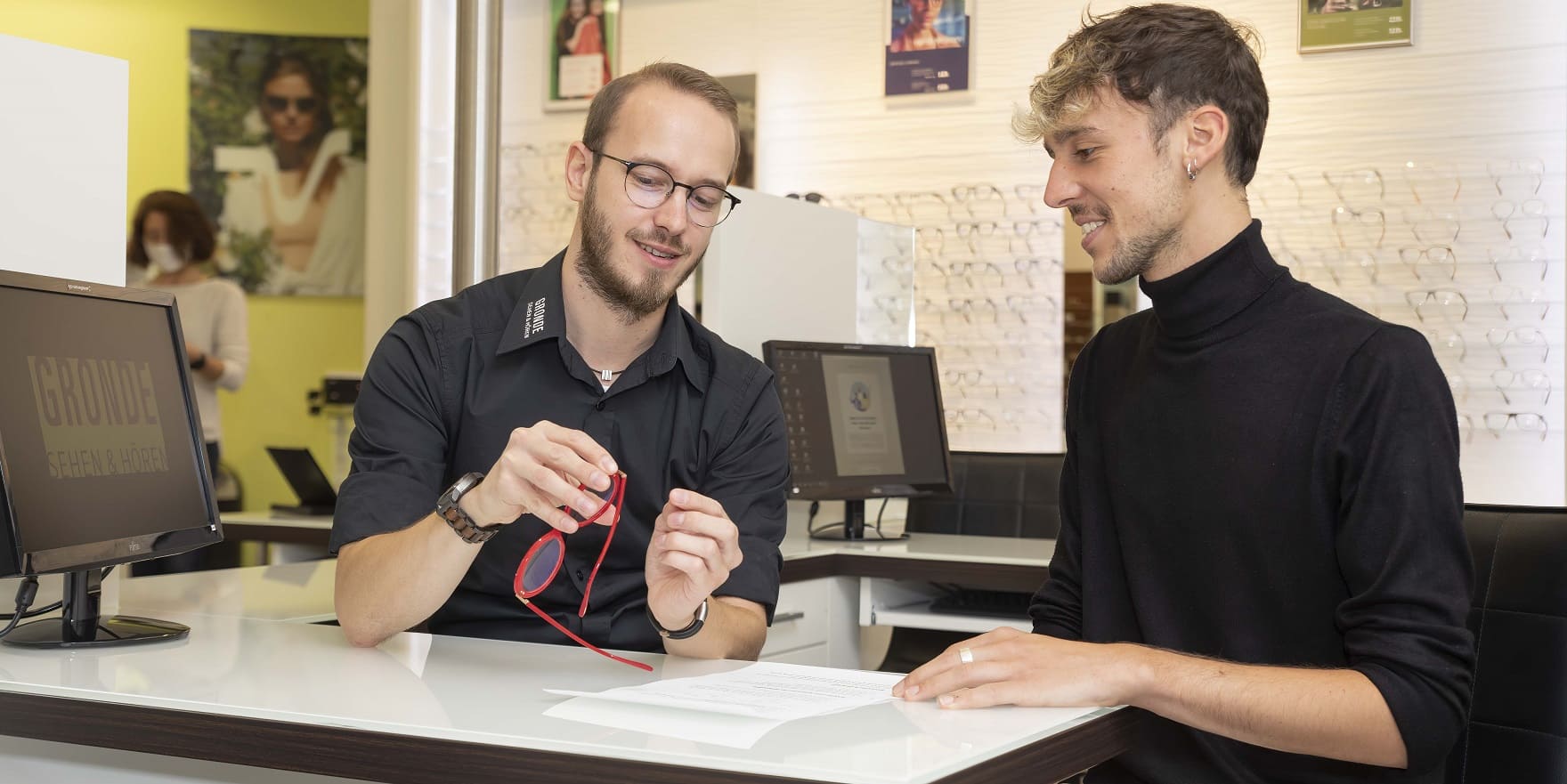 Ausbildungsleiter erklärt Azubi die Bestandteile einer Brille, Optiker Gronde