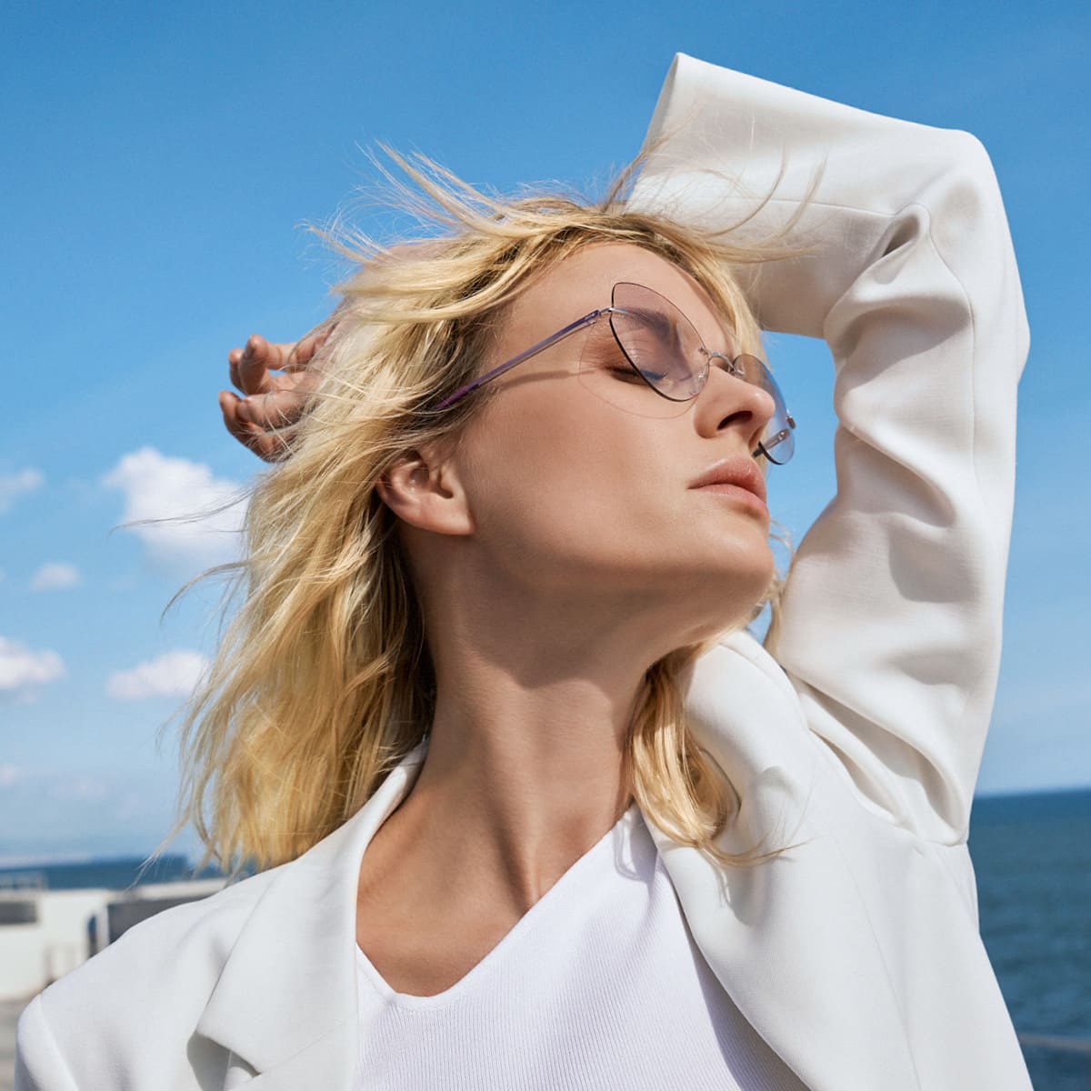 Blondine in weiß verträumt mit extravaganter, rahmenloser Silhouette Brille von Optiker Gronde